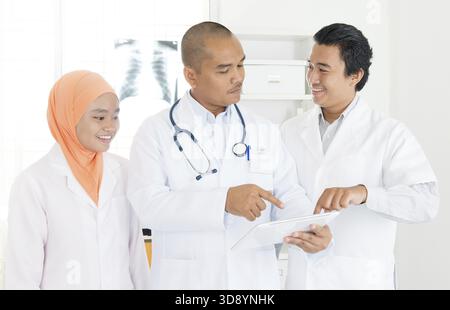Medical education, health care, people and medicine concept - group of doctors or interns with mentor meeting and taking notes at hospital. Southeast Stock Photo