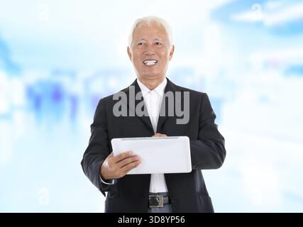 Asian senior businessman using tablet-pc standing office background Stock Photo