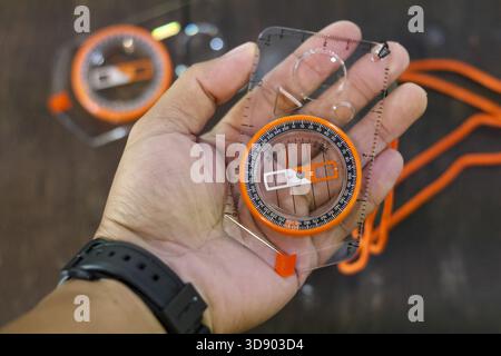 Person hand holding compass for navigation and direction. Feeling prepared for outdoor adventure, exploration, and survival on journey or hiking trip Stock Photo
