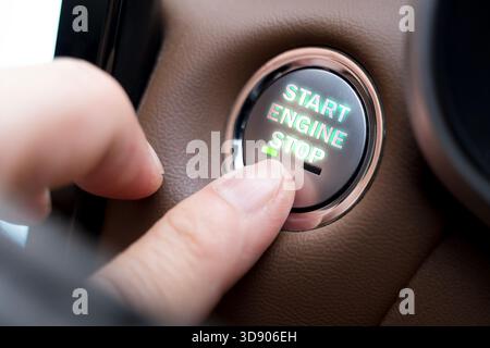 A close-up of a finger pressing a Start Engine Stop button in a modern car interior, representing technology, control, safety, and convenience. Ideal Stock Photo