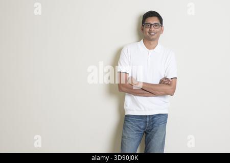 Portrait of handsome Indian guy standing on plain background with shadow and copy space Stock Photo