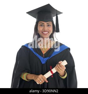 Happy Indian university student in graduation gown and cap holding diploma certificate. Portrait of Mixed-race Asian Indian and African American femal Stock Photo