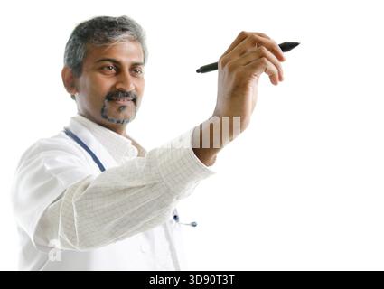 Indian doctor writing. Mature Indian male medical doctor drawing or sketching on blank space, standing isolated on white background. Handsome Indian m Stock Photo