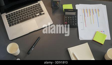 Busy business work meeting project planning setup on desk, featuring laptop, calculator, charts Stock Photo