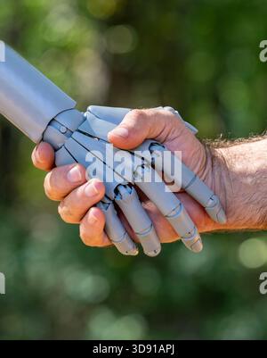 Robot and human hands. Robot and male hand handshake on green nature. Ai and human hands making handshake. Robotic hands interacting with human hand Stock Photo
