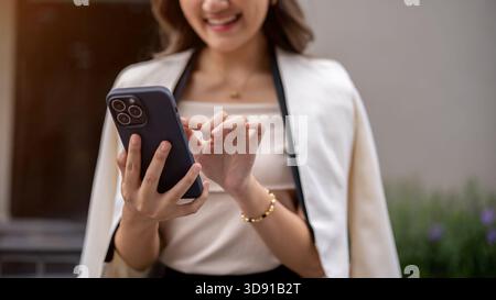 Close up of a woman's hands holding and touching on the smartphone while walking around the building. Urban Life, Chilling Outdoor. Stock Photo