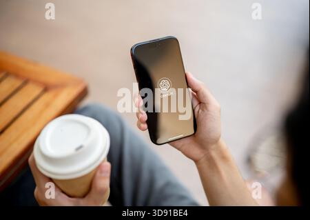 Chiang mai, Thailand - May 8th, 2025: Close up of man hand holding smartphone using ChatGPT application. Sitting on bench, Asking question or Chatting Stock Photo