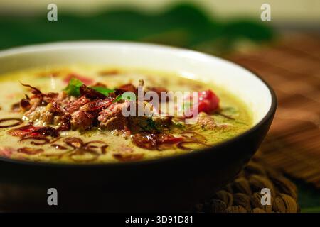Soto Betawi, Creamy beef or offal soup made with coconut milk, spices, tomato, onion, shallot, an Indonesian specialty. Banana leaf and coaster on the Stock Photo