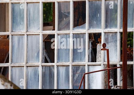 A horizontal shot focused on the detailed grid of many small window panes, covered in dirt and grime, with several panes missing or broken, revealing Stock Photo