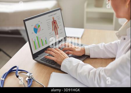 Doctor at laptop screen, general practitioner using online app for studying human anatomy Stock Photo