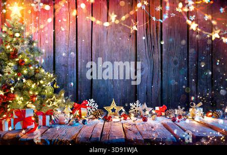 Christmas Tree With Gift Boxes On Rustic Wooden Table With Garland And Decorations - Abstract Defocused Lights Stock Photo