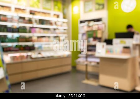 A busy, blurred interior of a modern retail shop or grocery store, with colorful merchandise on shelves and a customer near the counter, ideal as an a Stock Photo