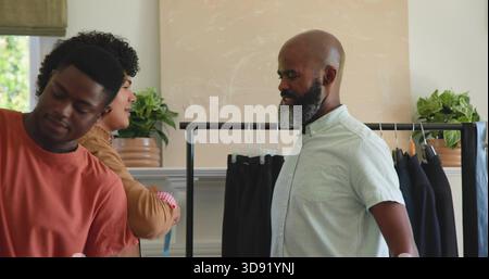 Observing mature man wearing light shirt evaluating pants and coats on store rack, copy space Stock Photo