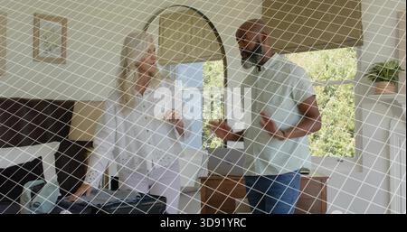 Packing woman in white blouse filling open suitcase on bed in bedroom, man gesturing near dresser Stock Photo