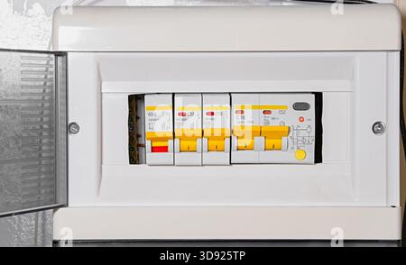 Close up of a residential electrical distribution board with circuit breakers and safety switch in a white plastic fuse box, illustrating home power c Stock Photo
