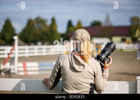 Woman holding digital camera at equestrian arena. Female photographer is preparing before sport event Stock Photo
