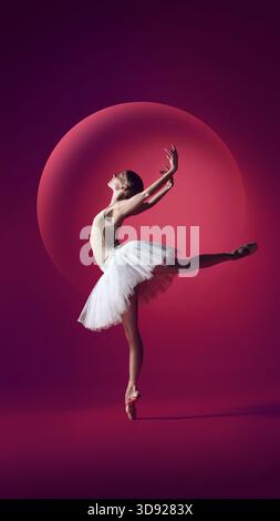Ballerina in dynamic arabesque against bold circular stage light Stock Photo