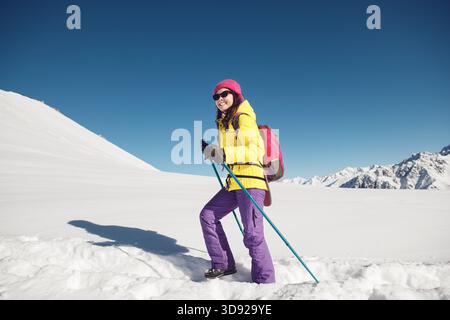 Solo Female Hiker Enjoying Sunny Winter Day in Snow-Covered Mountains Stock Photo