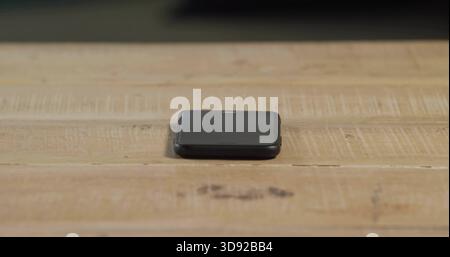 Resting folded black electronic device sitting centered on light wooden tabletop, showing scratches Stock Photo