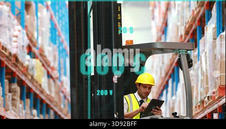 Checking man wearing yellow hard hat, hi-vis vest using tablet in warehouse, forklift overlays Stock Photo
