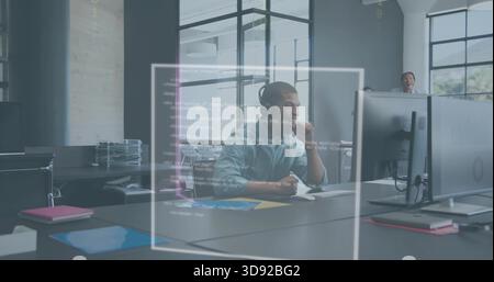 Reviewing developer wearing headset and light shirt debugging code on large monitor in open office Stock Photo