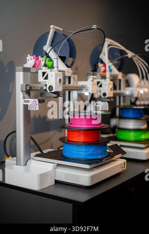 row of colorful 3d printing filament PLA material on environmentally friendly and recyclable paper cardboard spools on black carbon fiber background Stock Photo