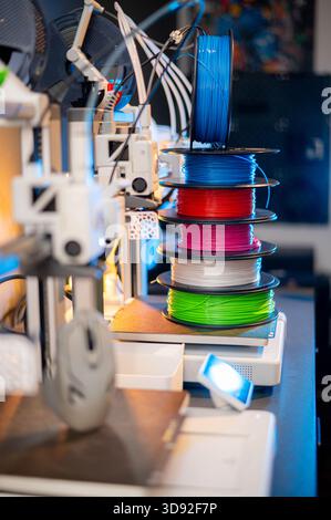 row of colorful 3d printing filament PLA material on environmentally friendly and recyclable paper cardboard spools on black carbon fiber background Stock Photo