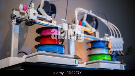 row of colorful 3d printing filament PLA material on environmentally friendly and recyclable paper cardboard spools on black carbon fiber background Stock Photo