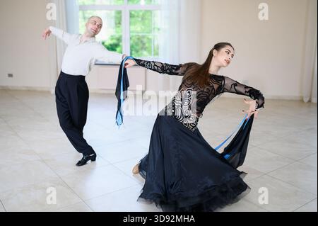 Pair of professional dancers, man and woman, dance in of dance floor. Harmonious combination and coordinated movements of classical dancers Stock Photo