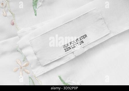 Fabric composition clothes label on white embroidered fabric background closeup Stock Photo