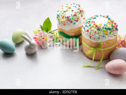 Traditional easter cakes with colorful sprinkles, accompanied by painted eggs, a bunny figurine, and spring flowers, creating a festive holiday scene Stock Photo