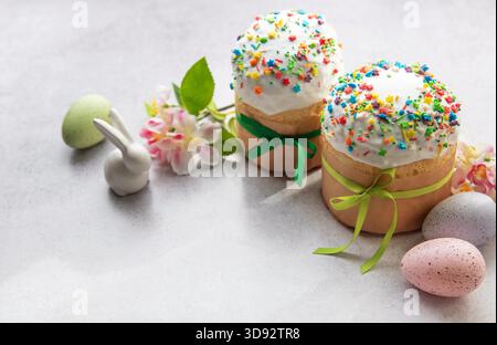 Traditional easter cakes with colorful sprinkles, accompanied by painted eggs, a bunny figurine, and spring flowers, creating a festive holiday scene Stock Photo