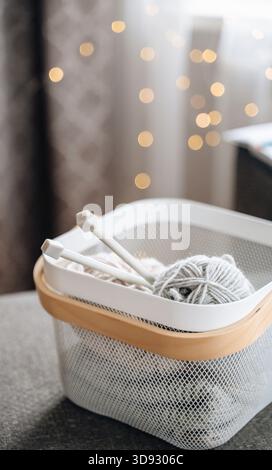 Cozy basket with yarn and knitting needles, perfect for knitting hobby and creative projects Stock Photo