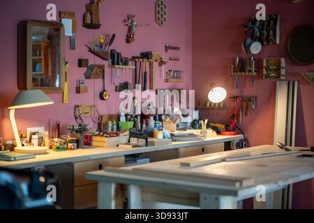 Cozy carpentry workshop interior workplace with tools, equipment and materials on wooden table. Stock Photo