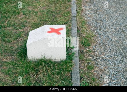 a red x marked on path stone along a gravel pathway Stock Photo