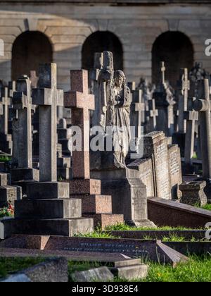 A statue of a woman clinging to a cross (Rock of Ages) among Victorian graves and colonnades in Brompton Cemetery, London. Stock Photo