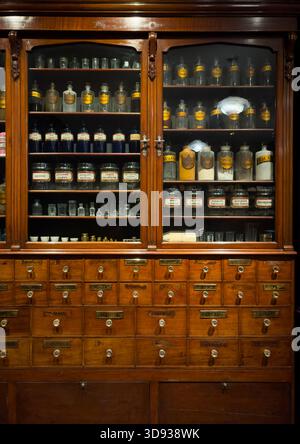 Antique wooden medicine cabinet filled with glass apothecary jars and drawers on display in the Science Museum, London. Stock Photo