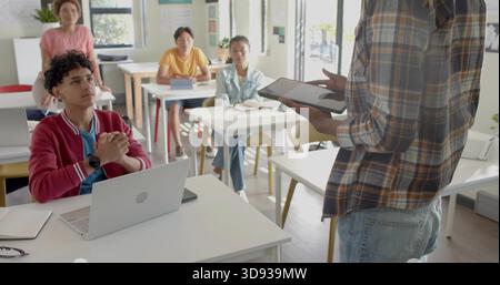 Presenting instructor in plaid shirt, jeans holding tablet addressing students in class, copy space Stock Photo