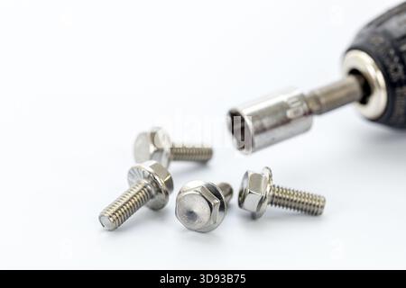 Four steel hex bolts arranged on a white surface near a close-up of a socket wrench with a metallic socket attachment, highlighting tools and hardware Stock Photo