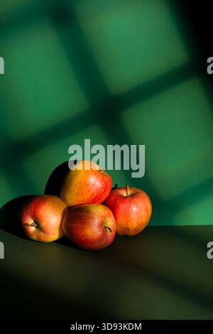 Apples pile on green background with window light effect. Stock Photo