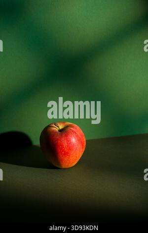 Red apple on green background with window light effect. Stock Photo