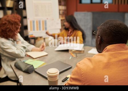 Diverse Young People Collaborating during Business Presentation in Library Stock Photo