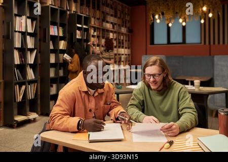Young Man and Black Man Studying Together in Library Stock Photo
