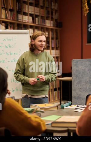 Young Man Teaching English Lesson to Diverse Students in Library Stock Photo