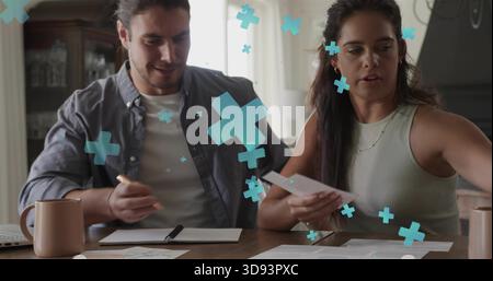 Sorting couple in tank top and open shirt, handling bills at wood table with turquoise overlays Stock Photo