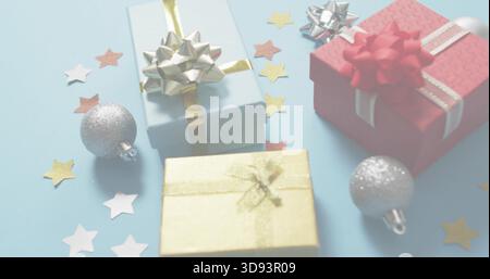 Displaying light-blue red gold wrapped gifts on pale-blue table with silver ornaments star confetti Stock Photo