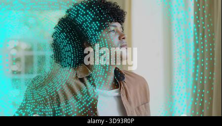Standing man wearing brown jacket over white tee, gazing at window with turquoise dotted overlay Stock Photo