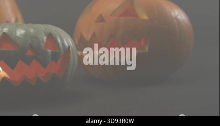 Glowing two carved pumpkins producing warm inner light on dark tabletop, soft reflections Stock Photo