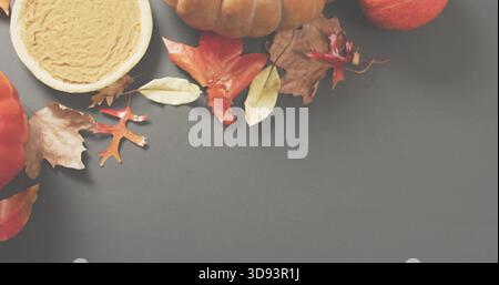 Displaying autumn harvest display resting on gray tabletop, pumpkins, pumpkin pie, apple, leaves Stock Photo