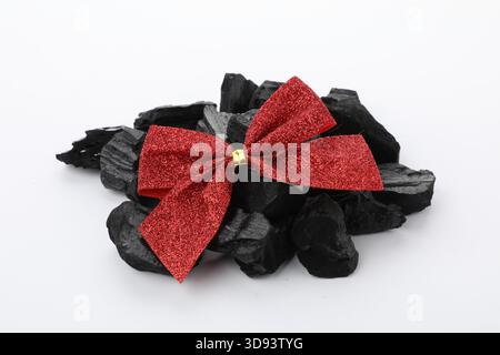Pieces of black coal with red bow isolated on white. Christmas tradition for kids Stock Photo